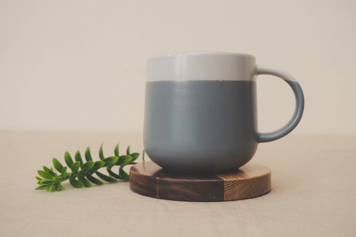 Mug on a two-toned round wood coaster.